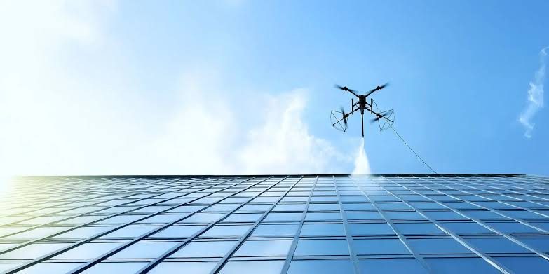 Drone cleaning the upper elevations of a glazed high-rise tower